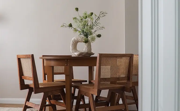 Wnętrze jadalni w stylu japandi z drewnianym stołem i nowoczesnymi krzesłami.