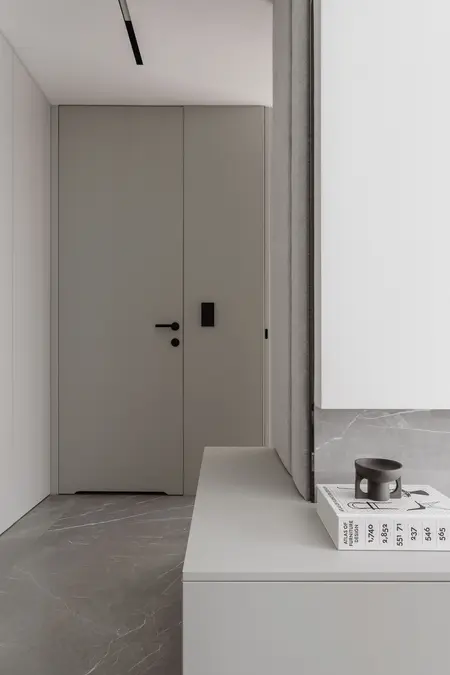 Nowoczesny przedpokój z szarymi ścianami, białym furniturem i marmurową podłogą.