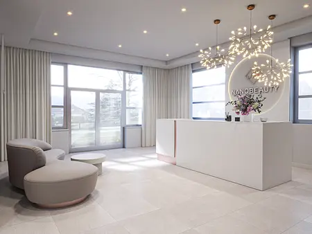 Recepcja minimalistyczna z białym biurkiem, szarym fotelem i nowoczesnym oświetleniem.