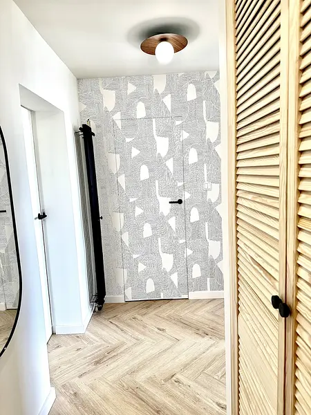 Przedpokój w stylu boho, eklektycznym i skandynawskim z drewnianą podłogą i szarymi ścianami.