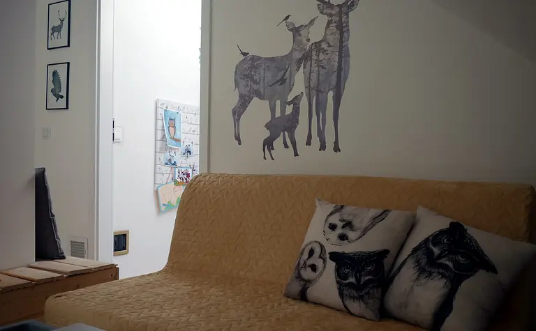 Wnętrze w stylu skandynawskim z żółtą sofą i muralem zwierząt.