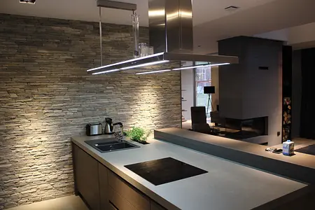 Wnętrze kuchni z minimalistycznym designem, kamienną ścianą i nowoczesnymi akcesoriami.