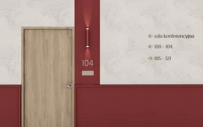 Korytarz z drewnianymi drzwiami, czerwonymi akcentami, industrialny i minimalistyczny design.