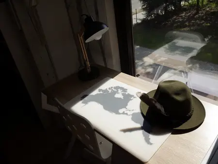 Biuro w stylu skandynawskim z drewnianym biurkiem i lampą.