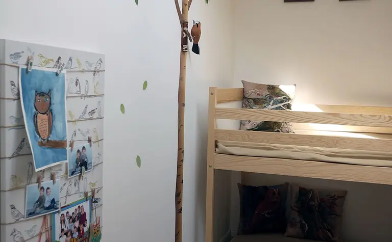 Pokój dziecięcy z łóżkiem piętrowym, drzewem i kolorowymi dodatkami w stylu skandynawskim.