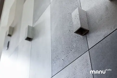 Betonowa ściana z minimalistycznym oświetleniem w industrialnym wnętrzu.