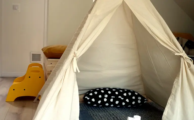 Pokój dla dzieci z tipi, poduszką w kropki i kolorowymi akcesoriami.