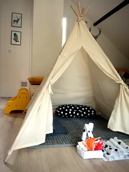 Pokój dla dzieci z tipi, poduszką w kropki i kolorowymi akcesoriami.
