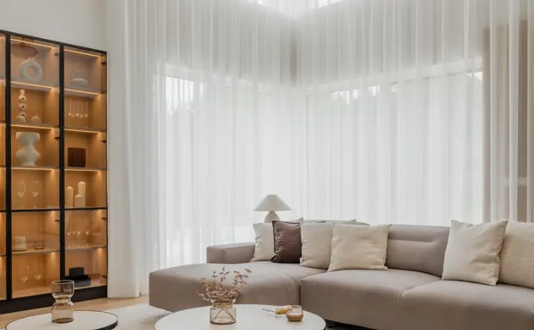 Minimalistyczny salon w stylu japandi z jasnymi meblami i dużymi oknami.