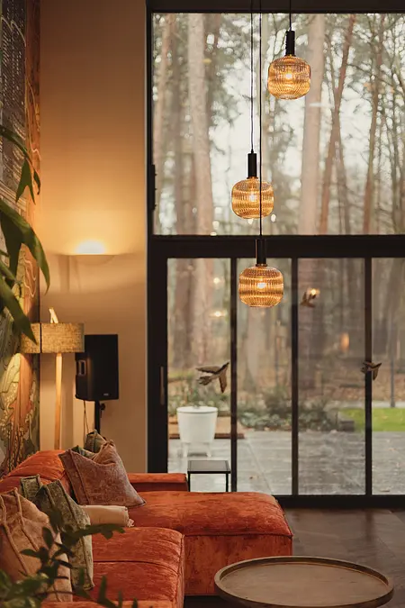Wnętrze salonu z pomarańczową sofą, drewnianymi akcentami oraz industrialnymi lampami. Dopamine decor, eklektyczny, rustykalny, vintage.