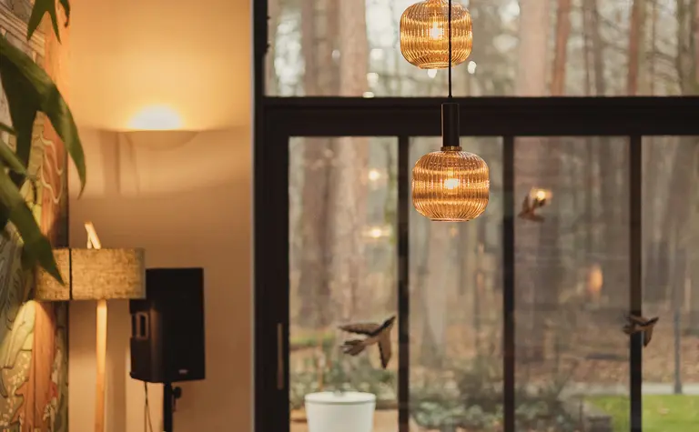 Wnętrze salonu z pomarańczową sofą, drewnianymi akcentami oraz industrialnymi lampami. Dopamine decor, eklektyczny, rustykalny, vintage.