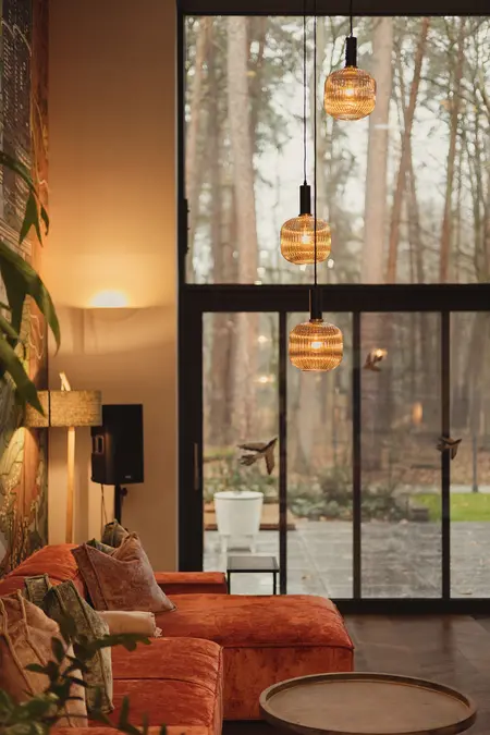 Wnętrze salonu z pomarańczową sofą, drewnianymi akcentami oraz industrialnymi lampami. Dopamine decor, eklektyczny, rustykalny, vintage.